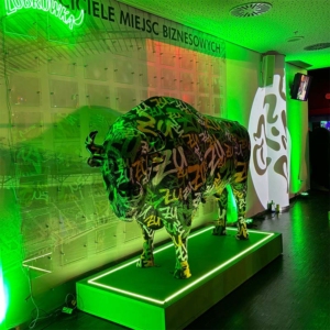 Sculpture d'un bison avec inscriptions, éclairée par une lumière verte, posée sur un socle lumineux dans une pièce.