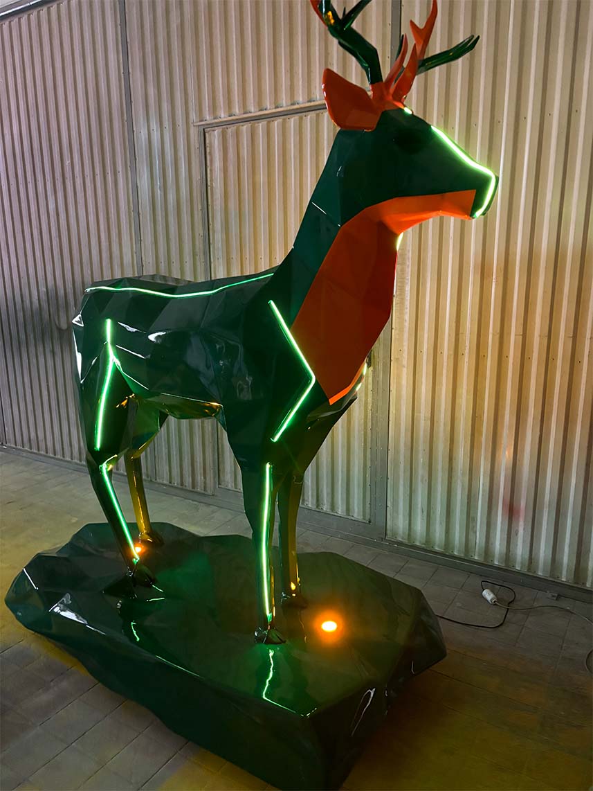 Cerfs Jägermeister avec Éclairage LED 11 Rzeźba jelenia z neonowymi światłami na stalowym podłożu w hali przemysłowej.