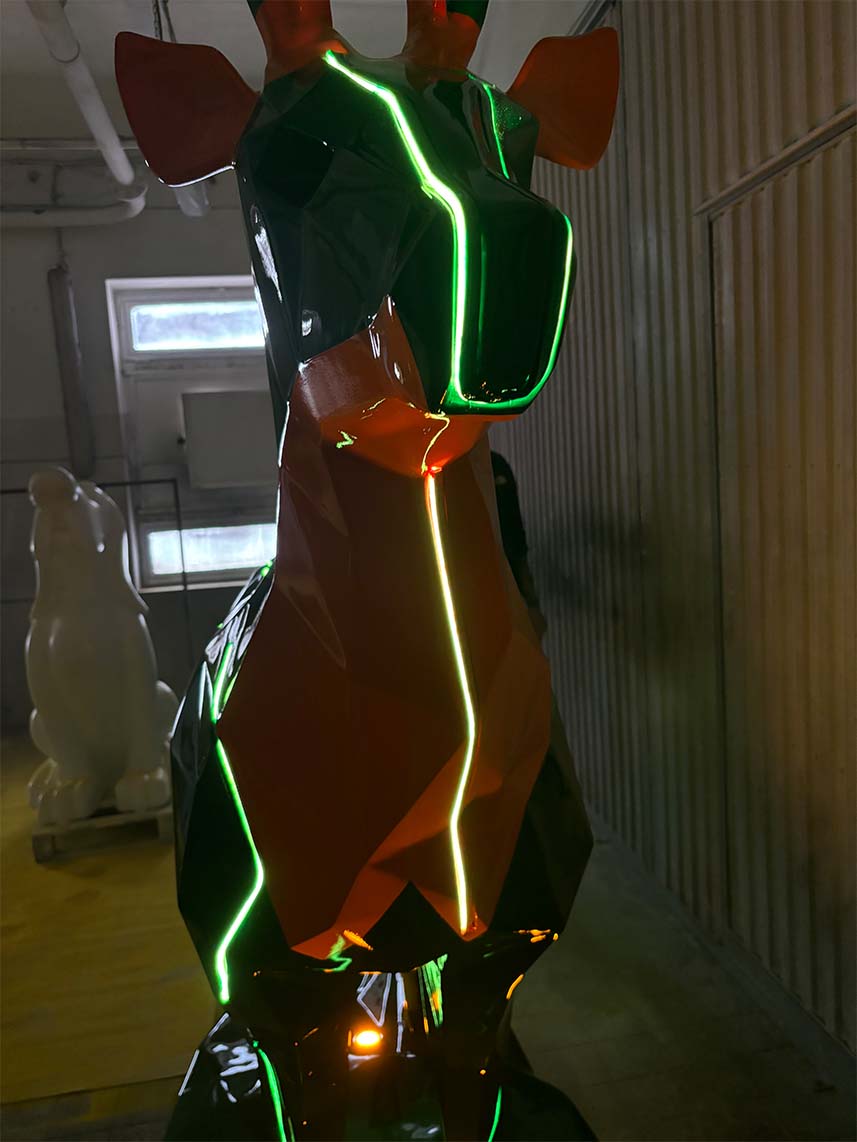 Cerfs Jägermeister avec Éclairage LED 4 Geometryczna rzeźba żyrafy z neonowymi zielonymi i pomarańczowymi światłami.