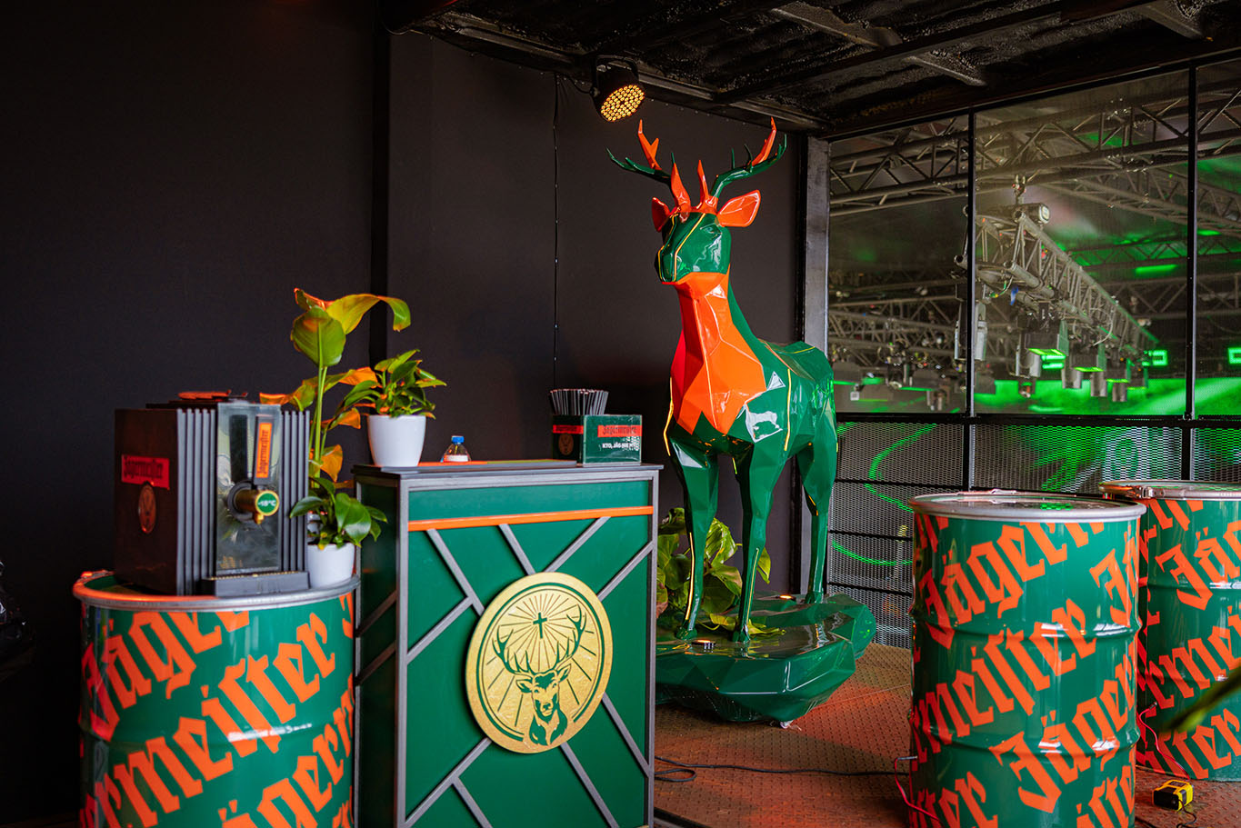 Cerfs Jägermeister avec Éclairage LED 1 Kolorowy, geometryczny jeleń oraz elementy dekoracyjne marki Jägermeister w barze ozdobionym roślinami.