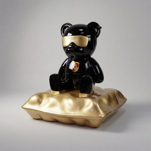 sculpture ours en fibre de verre noir brillant avec visière dorée et blason Porsche, style moderne sur coussin doré, déco ou pub